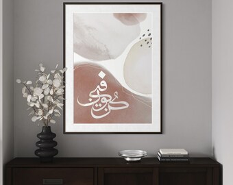 May include: Framed abstract art print with a watercolour design in white, beige, and terracotta hues. The artwork features white Arabic calligraphy. The print is displayed on a dark wood cabinet with a vase and decorative items.