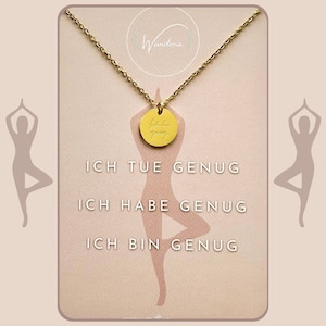 Könnte beinhalten: Goldkette mit einem runden Anhänger, auf dem "Ich tue genug, Ich habe genug, Ich bin genug" steht. Der Anhänger befindet sich auf einer weißen Karte mit einer Yoga-Silhouette und dem Wort "Wunderia" oben.