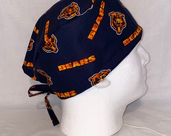 May include: A navy blue scrub hat with a repeating pattern of orange bears and the word "BEARS".
