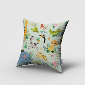 May include: A green pillow with a colorful jungle animal print. The animals include a giraffe, zebra, elephant, lion, toucan, monkey, turtle, flamingo, and crocodile. The pillow is perfect for a child's room or nursery.