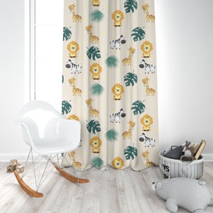 K&ouml;nnte beinhalten: Ein beigefarbener Vorhang mit einem sich wiederholenden Muster aus L&ouml;wen, Zebras, Giraffen und Palmenbl&auml;ttern. Der Vorhang h&auml;ngt in einem Raum mit einem wei&szlig;en Schaukelstuhl und einem grauen Korb aus Weide.