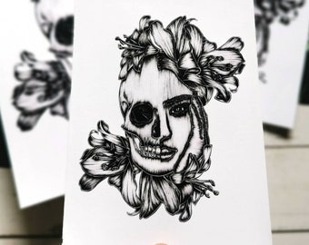 May include: Black and white illustration of a skull with flowers covering one side of the face. The skull is drawn in a realistic style with detailed features. The flowers are stylized and have a delicate appearance.