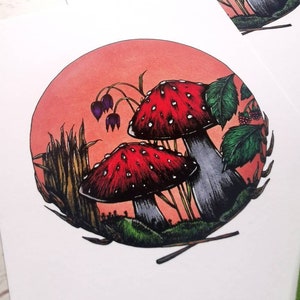 May include: A circular illustration of two red and white mushrooms with white spots in a forest setting. The mushrooms are surrounded by green leaves, tall grass, and a red-orange background.