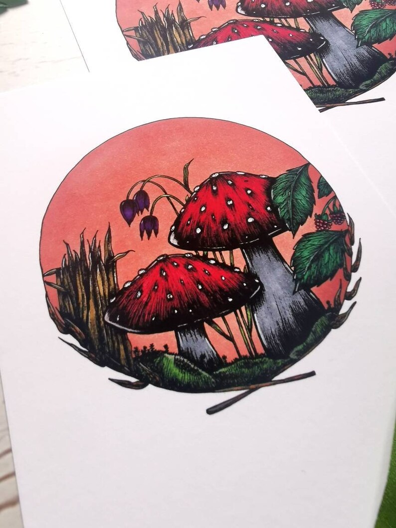 May include: A circular illustration of two red and white mushrooms with white spots in a forest setting. The mushrooms are surrounded by green leaves, tall grass, and a red-orange background.