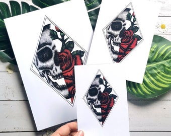 May include: Three white cards with black diamond shapes containing a black and white skull with a red rose. The rose is partially covering the skull.