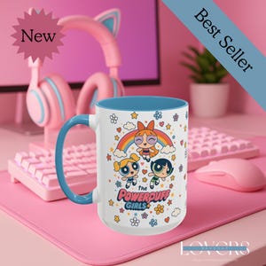 May include: A white ceramic mug with a blue interior and handle. The mug features a colourful illustration of the Powerpuff Girls with a rainbow and floral accents. The mug is labelled "Best Seller" and "New".