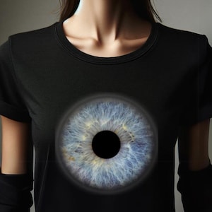 Könnte beinhalten: Ein schwarzes T-Shirt mit einem großen, blauen Augen-Motiv auf der Vorderseite.