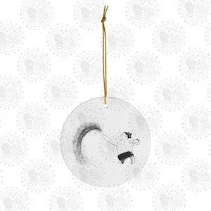 May include: A white ceramic ornament with a black and white illustration of a sumo wrestler throwing salt. The ornament has a gold string for hanging.