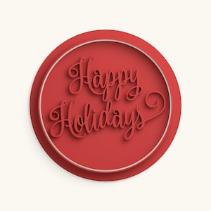 May include: A circular red plaque featuring the embossed text Happy Holidays in a cursive script font. The design includes a thin white circular border framing the central red area, creating a layered effect with a subtle drop shadow.