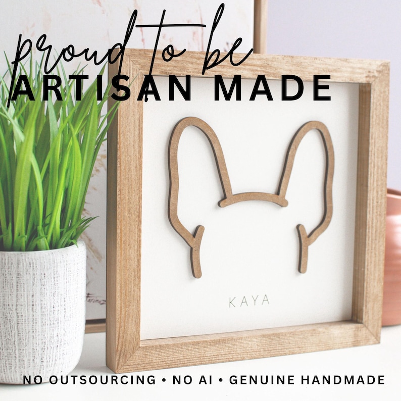 Puede incluir: Arte de pared enmarcado en madera con una silueta de perro. La obra de arte tiene un marco de madera de color claro y un fondo blanco. El nombre del perro, "Kaya", est&aacute; impreso en la parte inferior. El texto "proud to be ARTISAN MADE" est&aacute; en la parte superior.