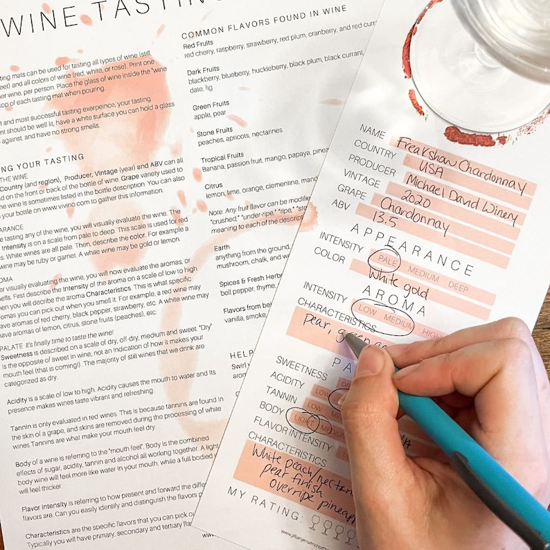 Puede incluir: Una hoja de cata de vino con una mano sosteniendo una pluma azul sobre la secci&oacute;n "Apariencia". La hoja est&aacute; llena de informaci&oacute;n sobre un vino Freakshaw Chardonnay, incluyendo el productor, la a&ntilde;ada, la uva, el ABV, la intensidad, el color, el aroma y las caracter&iacute;sticas. El vino se describe como de color blanco dorado p&aacute;lido y con un aroma a pera y manzana verde.