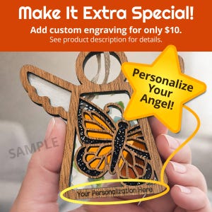a person's hand holding a wooden angel ornament with a butterfly design. The person is holding the ornament with a star-shaped tag attached to it, which appears to be a personalized decoration.