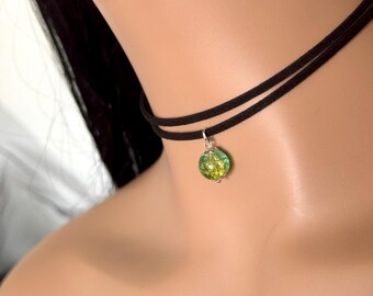 May include: Black double-strand choker necklace with a small, round, green and yellow pendant. The pendant has a silver-colored metal setting. The necklace is worn around the neck.