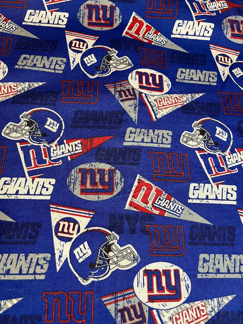 May include: Blue fabric with a repeating pattern of the New York Giants logo. The logo features the team's name, "Giants", and the letters "NY" in a circle. The fabric also includes the team's helmet.