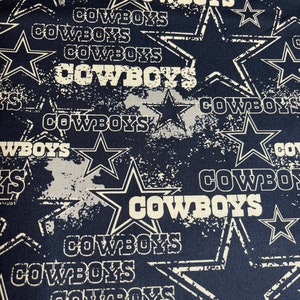 May include: A navy blue fabric with a white distressed pattern of stars and the word "COWBOYS" repeated throughout.