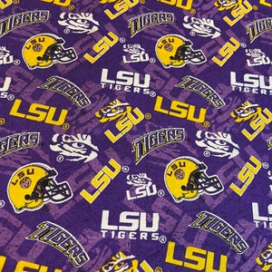May include: Purple fabric with a repeating pattern of the LSU Tigers logo in yellow and white. The logo includes the words "LSU Tigers" and a tiger head.