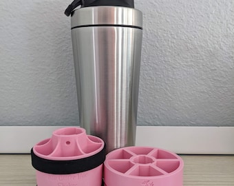 Peut inclure: Une bouteille de shaker en acier inoxydable avec un couvercle noir et une base en plastique rose avec le texte "The Cocktail Bar Shaker".