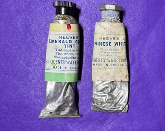 May include: Two vintage Reeves Students' Water Color paint tubes. One is labeled "Emerald Green Tint" and the other "Chinese White." Both tubes are made in England and have text in multiple languages.