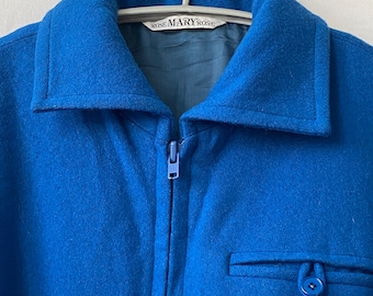 Op de afbeelding: Een blauw jack met rits en een enkele zak aan de linkerkant. Het jack heeft een label met de tekst "Mary Rose".