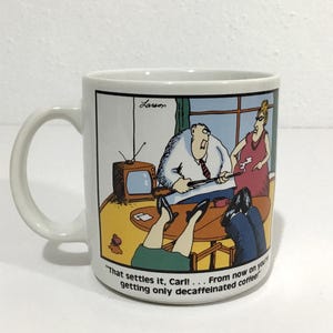 May include: White ceramic mug featuring a cartoon scene with a man, woman, and television. The mug has the text "That settles it, Carl! ... From now on you're getting only decaffeinated coffee!" and the artist's signature.