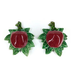 May include: Two ceramic apple wall hooks with green leaves. The apples are a deep red color.