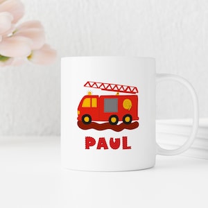 Könnte beinhalten: Weiße Keramiktasse mit einer roten Feuerwehrwagen-Illustration und dem Namen "PAUL" in roten gestickten Buchstaben.