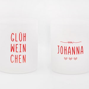 May include: Two frosted glass mugs with handles. One mug has the red text "GL&Uuml;H WEIN CHEN", and the other has "von JOHANNA" with three hearts. The mugs are white and sit on a white background.