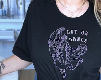 May include: Black t-shirt with a purple graphic of a woman with wings dancing. The text "Let Us Dance" is printed on the shirt.