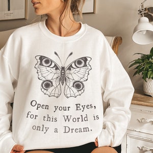 May include: White sweatshirt featuring a black and white butterfly graphic and the text "Open your Eyes, for this World is only a Dream."