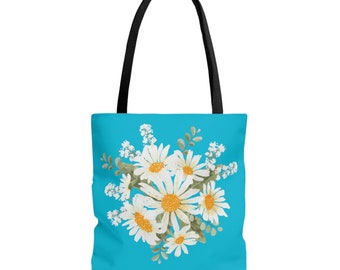 May include: A blue tote bag with a white daisy floral print. The daisies have yellow centers and green leaves.