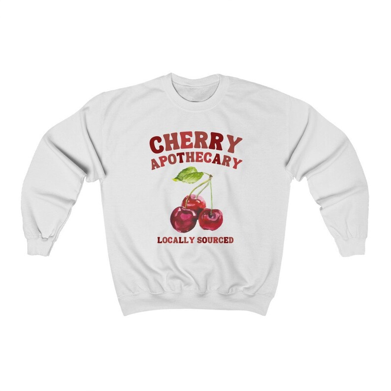 May include: White sweatshirt with a red and white graphic of two cherries with green leaves and the text "CHERRY APOTHECARY LOCALLY SOURCED".