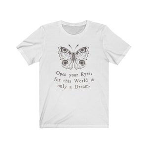 May include: White t-shirt featuring a detailed butterfly illustration in shades of gray. The text "Open your Eyes, for this World is only a Dream" is printed below the butterfly. A classic crew neck tee.