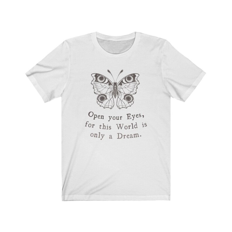 May include: White t-shirt featuring a detailed butterfly illustration in shades of gray. The text "Open your Eyes, for this World is only a Dream" is printed below the butterfly. A classic crew neck tee.