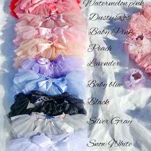 May include: A stack of ten tulle skirts in various colors, including red, watermelon pink, dusty rose, baby pink, peach, lavender, baby blue, black, silver gray, and snow white. Each skirt has a satin bow.