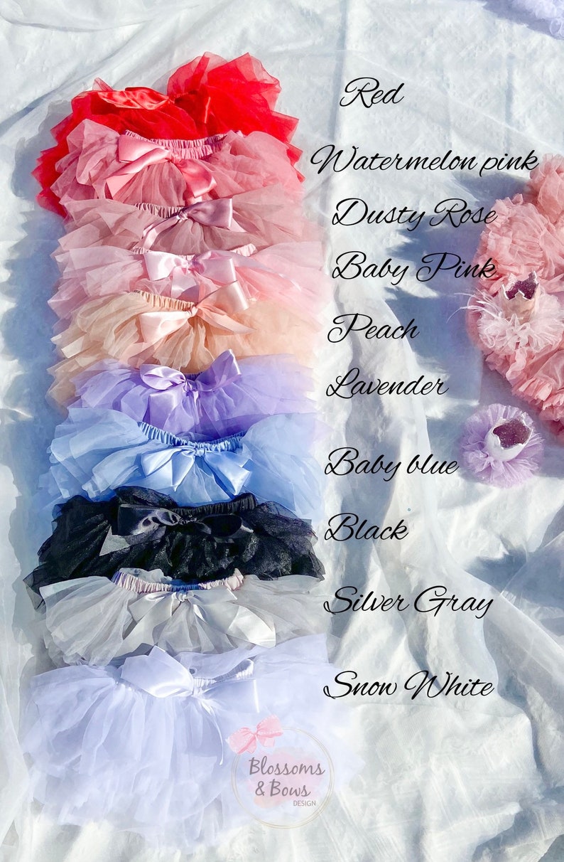 May include: A stack of ten tulle skirts in various colors, including red, watermelon pink, dusty rose, baby pink, peach, lavender, baby blue, black, silver gray, and snow white. Each skirt has a satin bow.