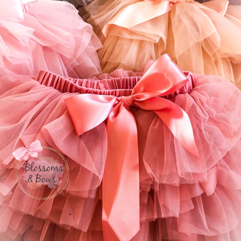 May include: A pink tulle tutu skirt with a large pink satin bow. The skirt has multiple layers of tulle and is perfect for a special occasion.
