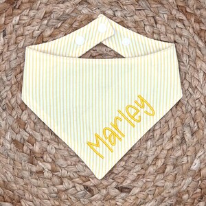 以下が含まれることがあります： 黄色と白のストライプの bandana に、黄色い糸で「Marley」という名前が刺繍されています。