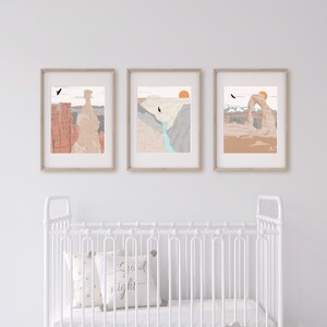 May include: Three framed prints of desert landscapes with a sunset, a canyon, and a natural arch. The prints are in a white room with a white crib in the foreground.