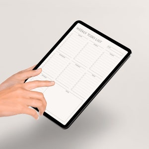 May include: A black tablet with a weekly to-do list app open. The app has sections for each day of the week, with checkboxes for tasks. The tablet is being held by a person's hands.