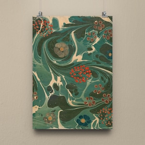 Op de afbeelding: Een ingelijste print met een abstract ontwerp van wervelende patronen in teal, donkergroen en wit. Rode, besachtige clusters en bloemaccenten in blauw en bruin zijn over het oppervlak verspreid. Het kunstwerk wordt op een neutraal gekleurde muur getoond.