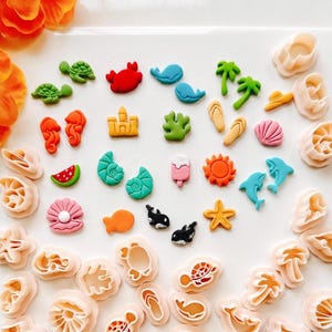 Może przedstawiać: Zestaw 30 kolorowych plastikowych foremek do ciasteczek w kształcie różnych przedmiotów z motywem letnim i plażowym, w tym muszli, gwiazd morskich, palm, klapek, lodów w wafelkach i innych.