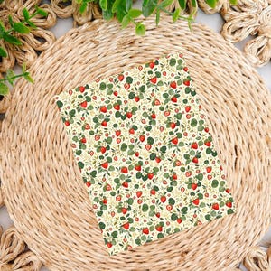 May include: A rectangular card featuring a repeating pattern of red strawberries, green leaves, and small white flowers on a pale cream background. The design covers the entire surface of the card with a dense, botanical arrangement of fruit and foliage.