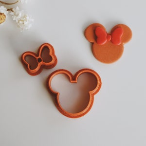 Peut inclure: Un ensemble de trois emporte-pièces en plastique brun en forme de tête de souris, d'un nœud et d'une tête de souris avec un nœud.