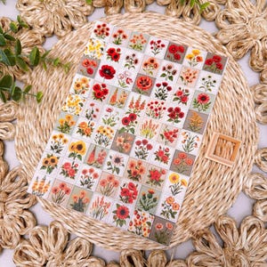 May include: A rectangular sheet of stickers featuring a grid of individual square illustrations of various flowers in shades of red, orange, and yellow. Each small square depicts a different botanical arrangement, including poppies, sunflowers, and wildflowers.
