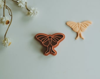 May include: Two brown and orange butterfly cookie cutters. One is a more detailed design with a darker brown color. The other is a simpler design with a lighter orange color.
