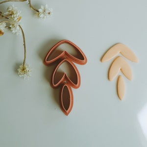 May include: A set of three red plastic cookie cutters shaped like leaves, and a set of three yellow plastic cookie cutters shaped like leaves.