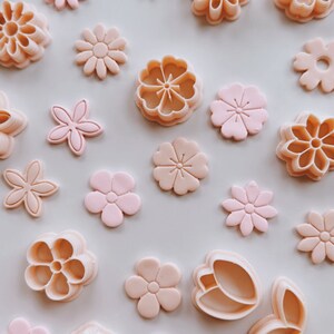 May include: A set of 18 pink and green plastic cookie cutters in various flower and tulip shapes.