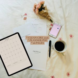 May include: A digital planner displayed on a tablet screen showing a May 2026 calendar, alongside printed planner pages, a smartphone with a calendar app, a black pen, a white mug of black coffee, and a small bouquet of pink roses.