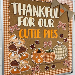May include: A cork bulletin board with a brown and white gingham border featuring the text THANKFUL FOR OUR CUTIE PIES, decorated with paper cutouts of pumpkin pie slices, various patterned pumpkins, brown autumn leaves, and bows.