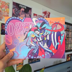 May include: A colorful illustration of two cartoon characters, one with blue hair and a red and black striped suit, and the other with a red and black jester hat and a blue and white suit. The characters are embracing and the background is a pink and blue heart with the word "OZZY" in neon pink letters.
